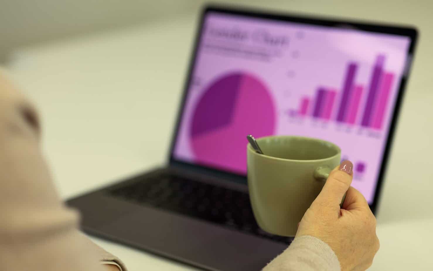 Business analytics with laptop and coffee for data analysis.